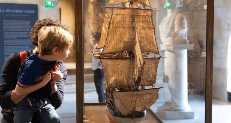 Un enfant et sa mère admirant un modèle de voilier