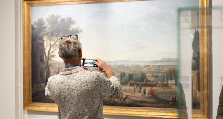 Visiteur prenant en photo un tableau de scène maritime