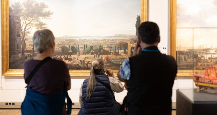 Visiteurs devant un tableau, avec des audioguides