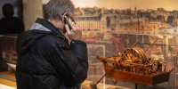 Visiteur avec un audioguide devant un modèle de bateau