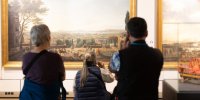 Visiteurs devant un tableau, avec des audioguides